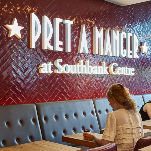 Pret A Manger interior with customer sat in front of large logo 