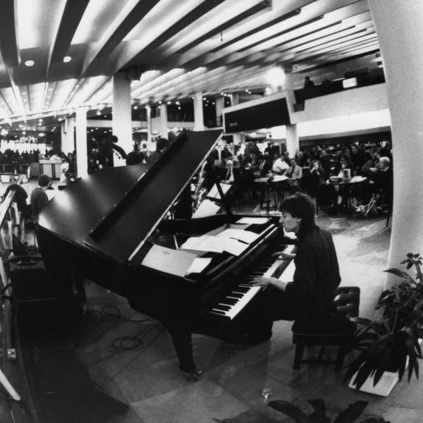 A man playing a grand piano in an auditorium