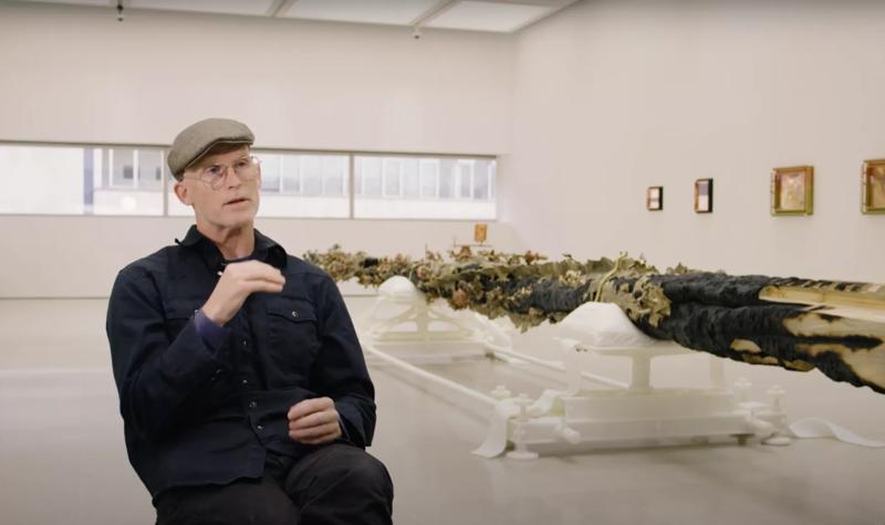Matthew Barney sits talking to camera in his exhibition Redoubt at Hayward Gallery