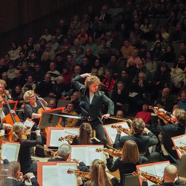 A photo of an orchestra conductor on stage.