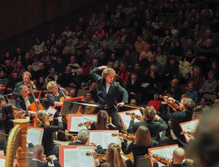 A photo of an orchestra conductor on stage.