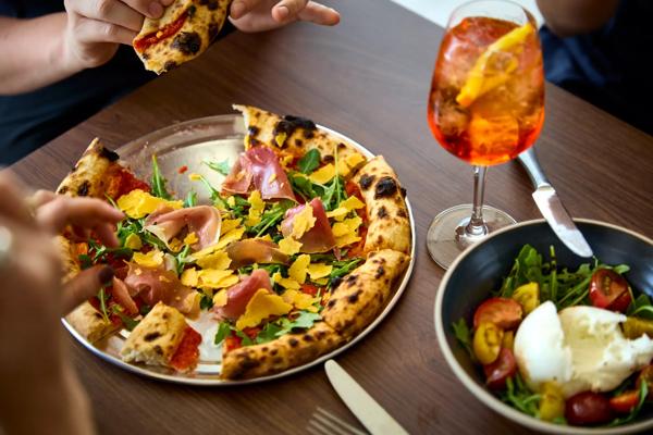 Pizza, Aperol spritz and burrata salad on a table at the Festival Bar & Kitchen