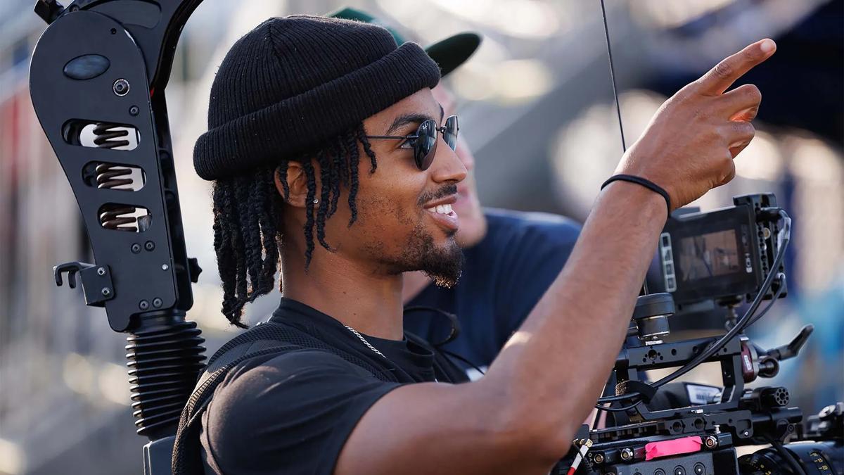 A camera operator smiles while filming at fairgrounds