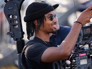 A camera operator smiles while filming at fairgrounds