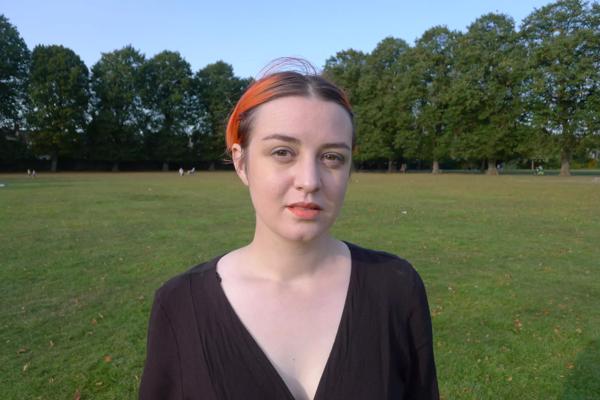 A woman with orange highlights standing in a park