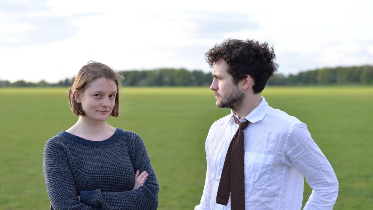 Couple standing on field looking at camera.