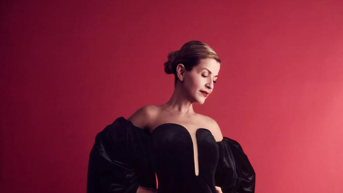 Violinist Anne-Sophie Mutter in a black silk dress on a deep red backdrop