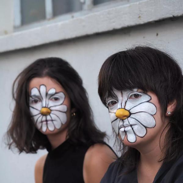 Two people with white daisies painted on their faces 