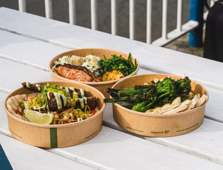 Three paper takeaway bowls filled with food