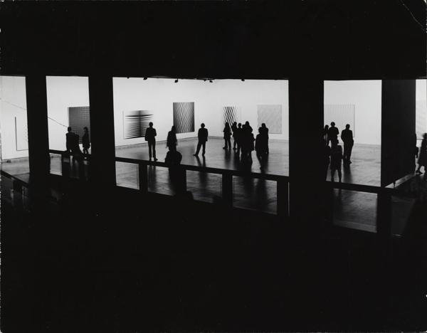 Visitors the Hayward Gallery's 1971 exhibition of the works of Bridget Riley take in the art work.