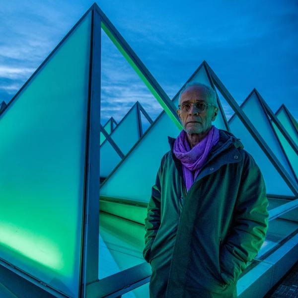 Artist David Batchelor stands on the roof of the Hayward Gallery beside the pyramid windows, illuminated by his installation piece Sixty Minute Spectrum