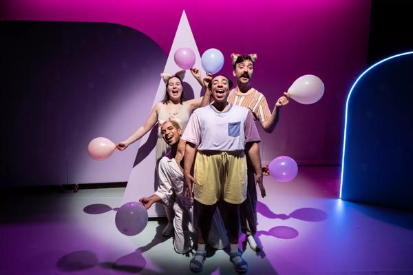 4 performers hold pastel coloured balloons and sing. 