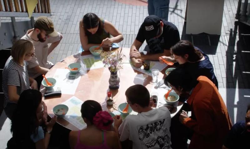 People sitting on a circle table eating a rice soup