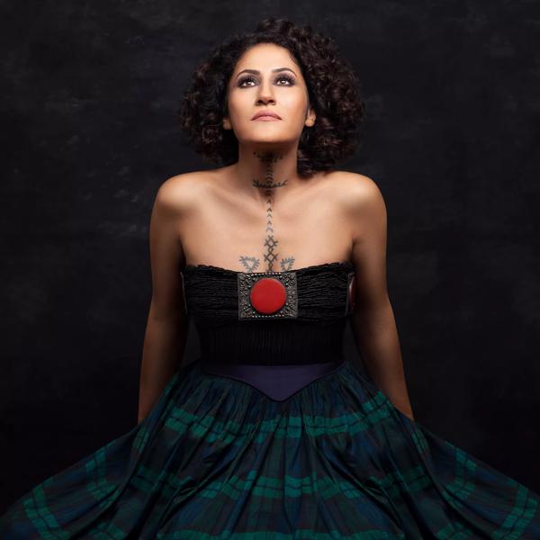 Contemporary Kurdish singer in a dark tartan dress