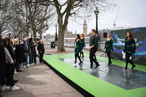 Image of dancers dressed in green Irish Dancing on a light up green dance floor on the Queen's Walk.