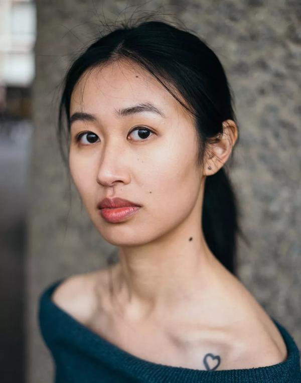 Christy Ku with her hair tied back, wearing an off the shoulder green jumper