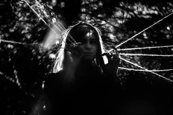 Musical artist Hekla surrounded by foliage and strings 