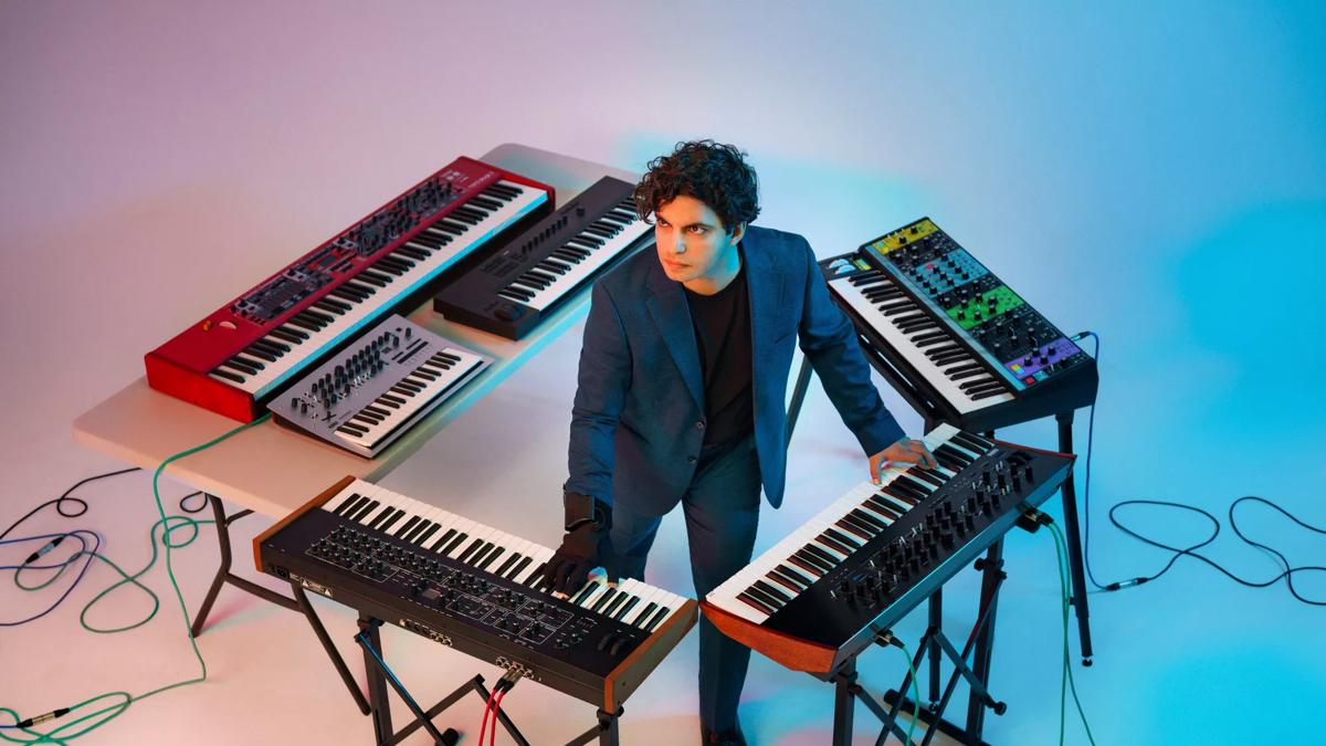 Zubin Kanga standing in the middle of multiple keyboards