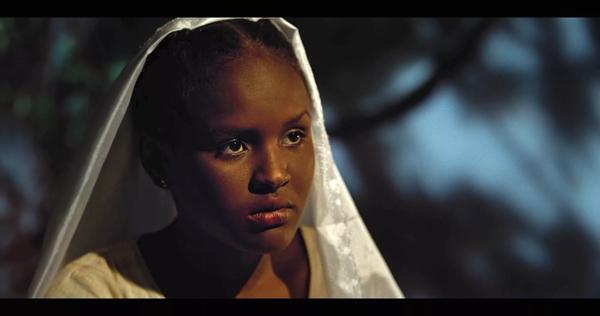 A young Sudanese girl sits looking beyond camera in a white silk veil.