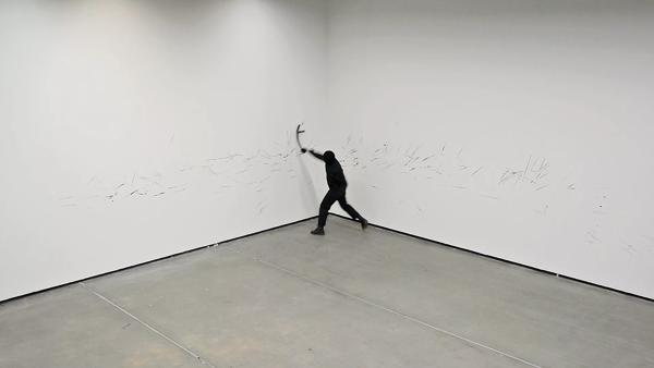 Person dressed in black writing on the walls around them 
