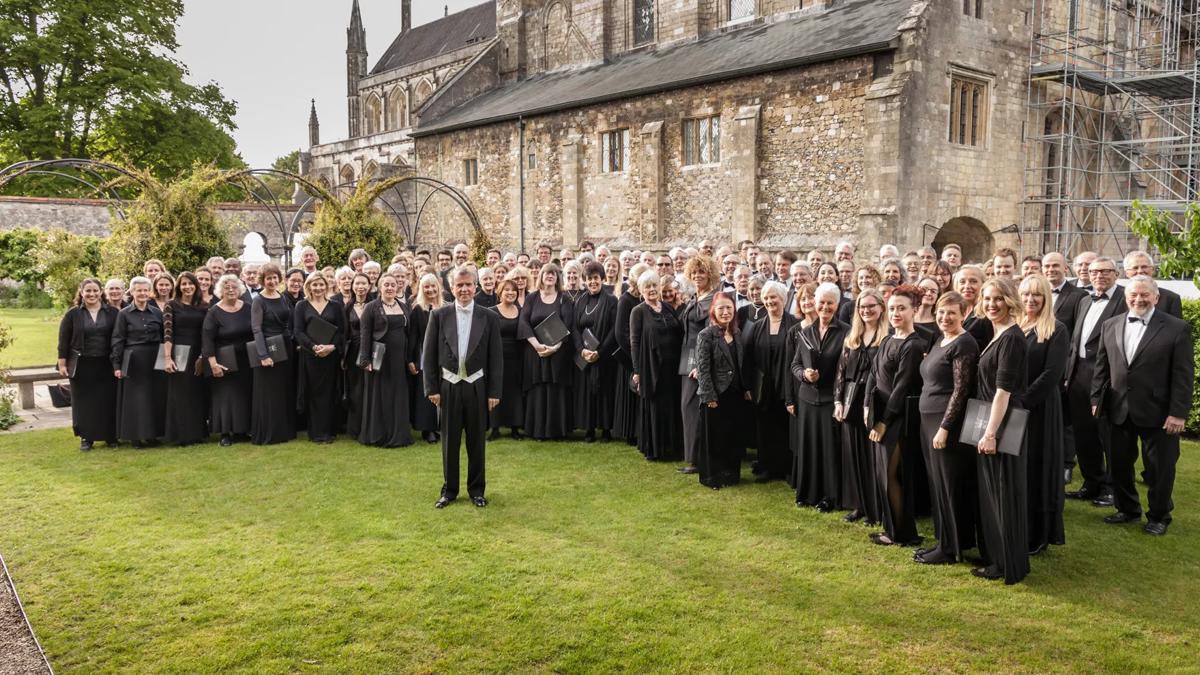 Royal Choral Society choir dressed in black in front of an old stone building 