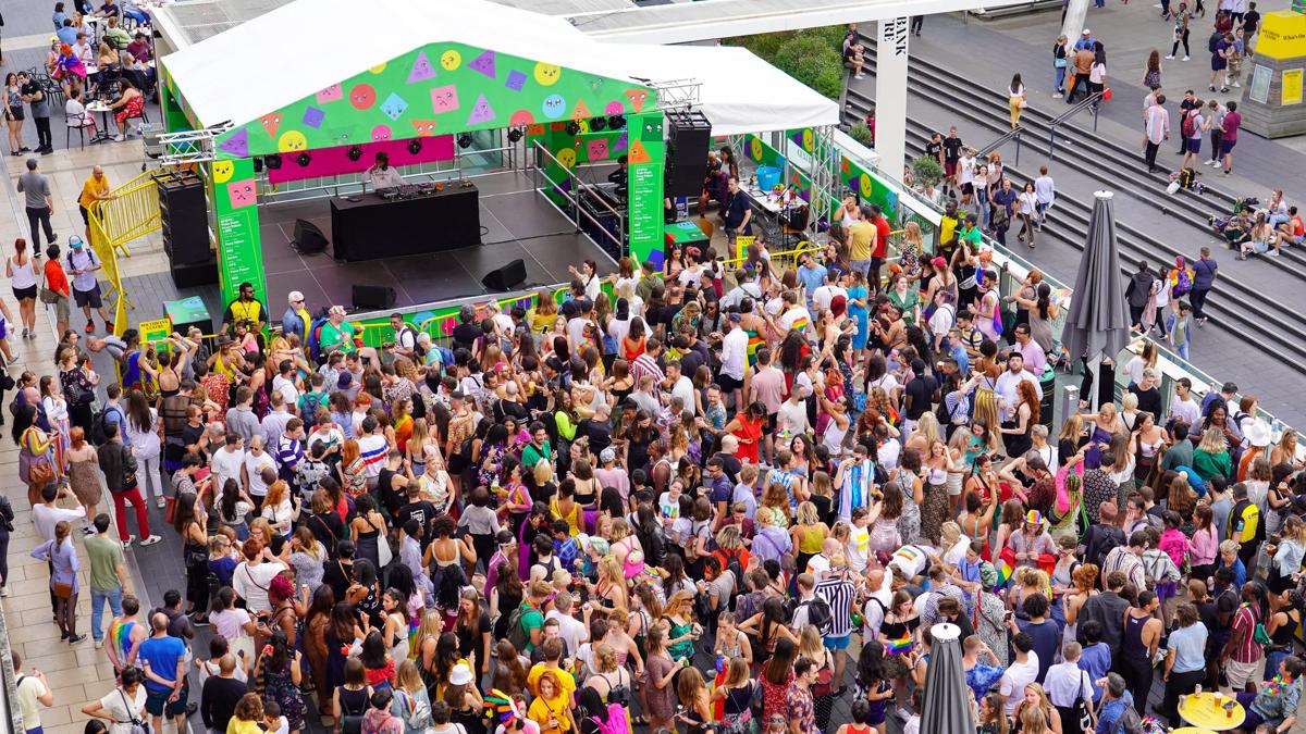Outdoor Riverside terrace stage with a large audience wearing colourful clothing