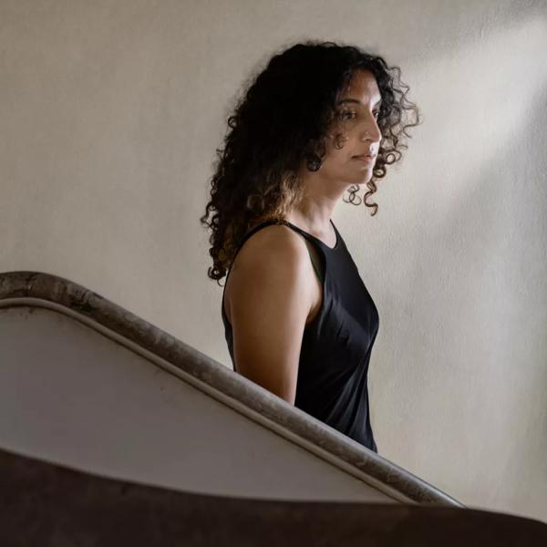 Sheena Patel stands on a staircase wearing a black silk dress