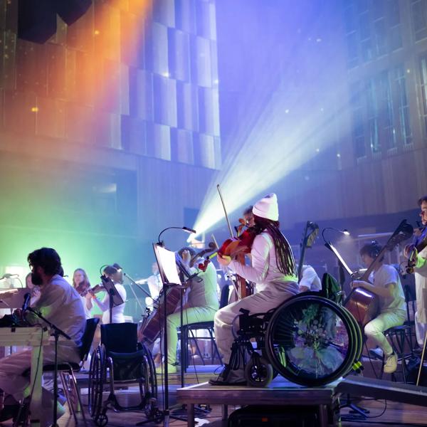 Paraorchestra: Trip the Light Fantastic at the Bristol Beacon - the orchestra wear all white and are surrounded by colourful lights.