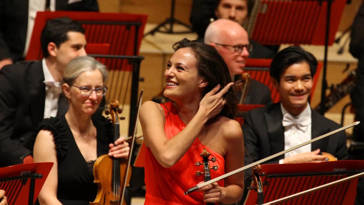 Nicola Benedetti smilling and holding her violin at the end of a performance