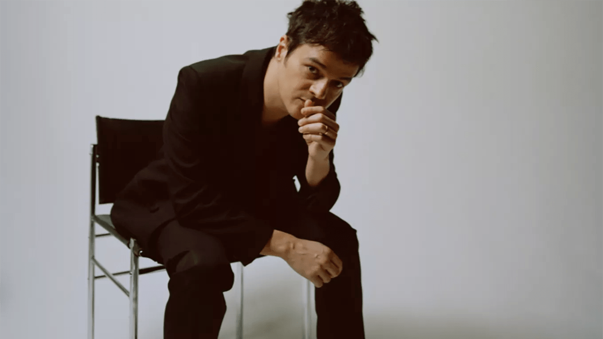 Jamie Cullum sits on a chair against a white background
