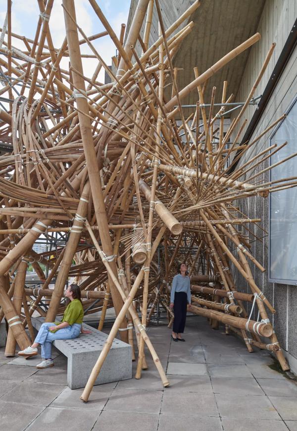 People walking through a large bamboo structure