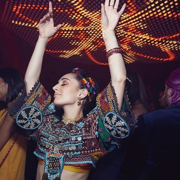 A dancer wearing an embroidered top with their hands in the air