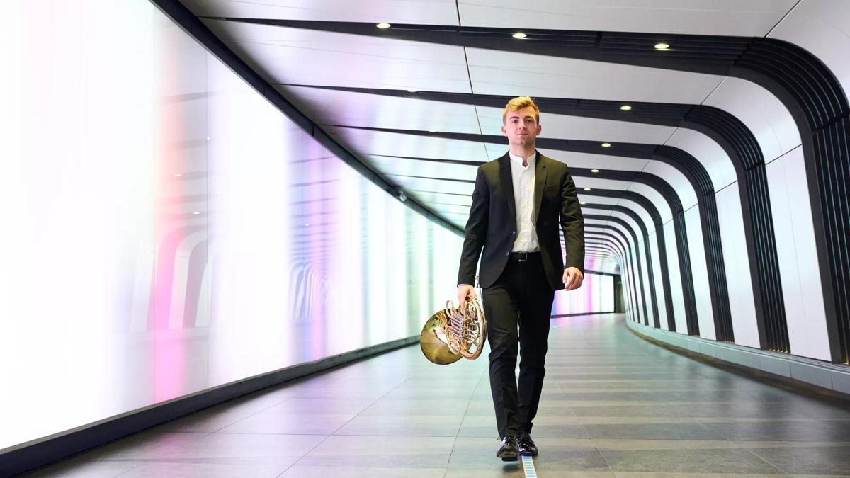 French Horn player Ben Goldscheider walks through a tunnel