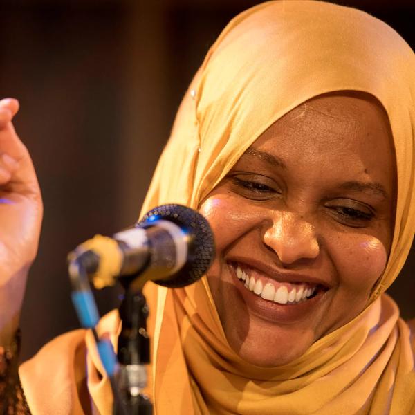 Asha Lul Mohamud Yusuf standing at a microphone, clicking her fingers.