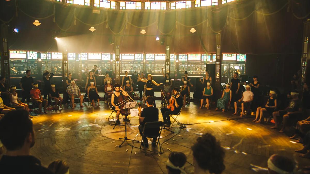 A string group surrounded by an audience wearing blindfolds