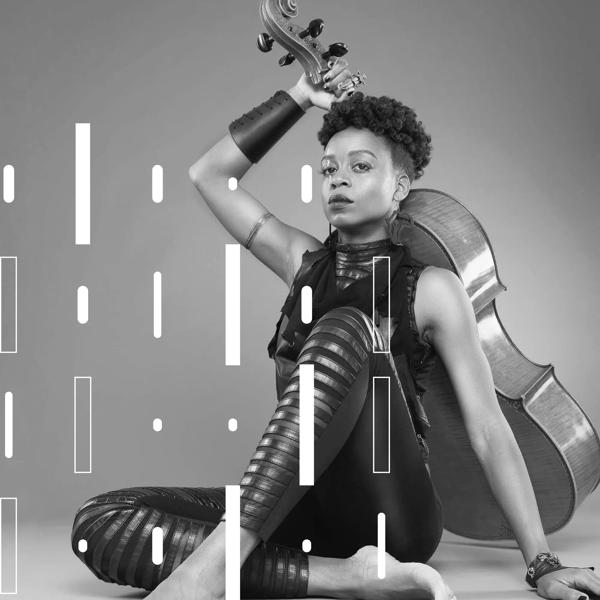 Artist Ayanna Witter-Johnson sits in a black outfit cross legged on the floor holding the cello upright behind her