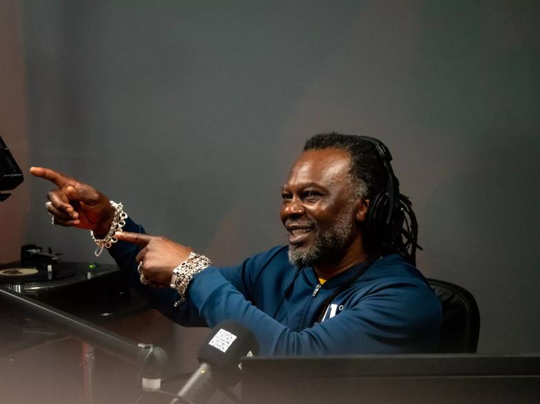 Levi Roots in a radio station pointing at a a microphone