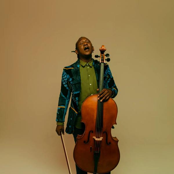Celloist Abel Selaocoe singing while holding his cello 