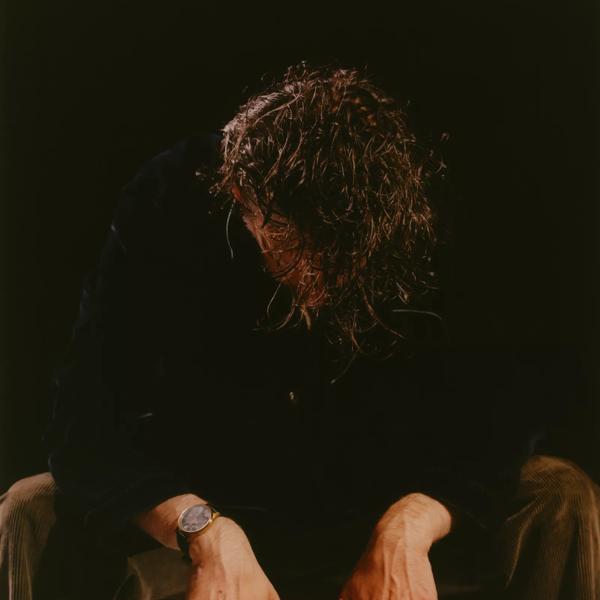 A man wearing black facing downwards towards his hands.