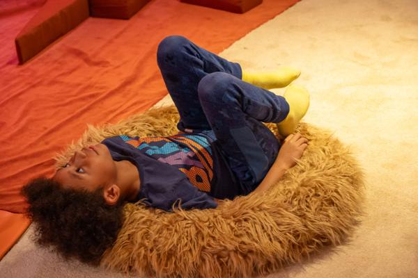 Child lying on their back on a fluffy yellow bean bag.