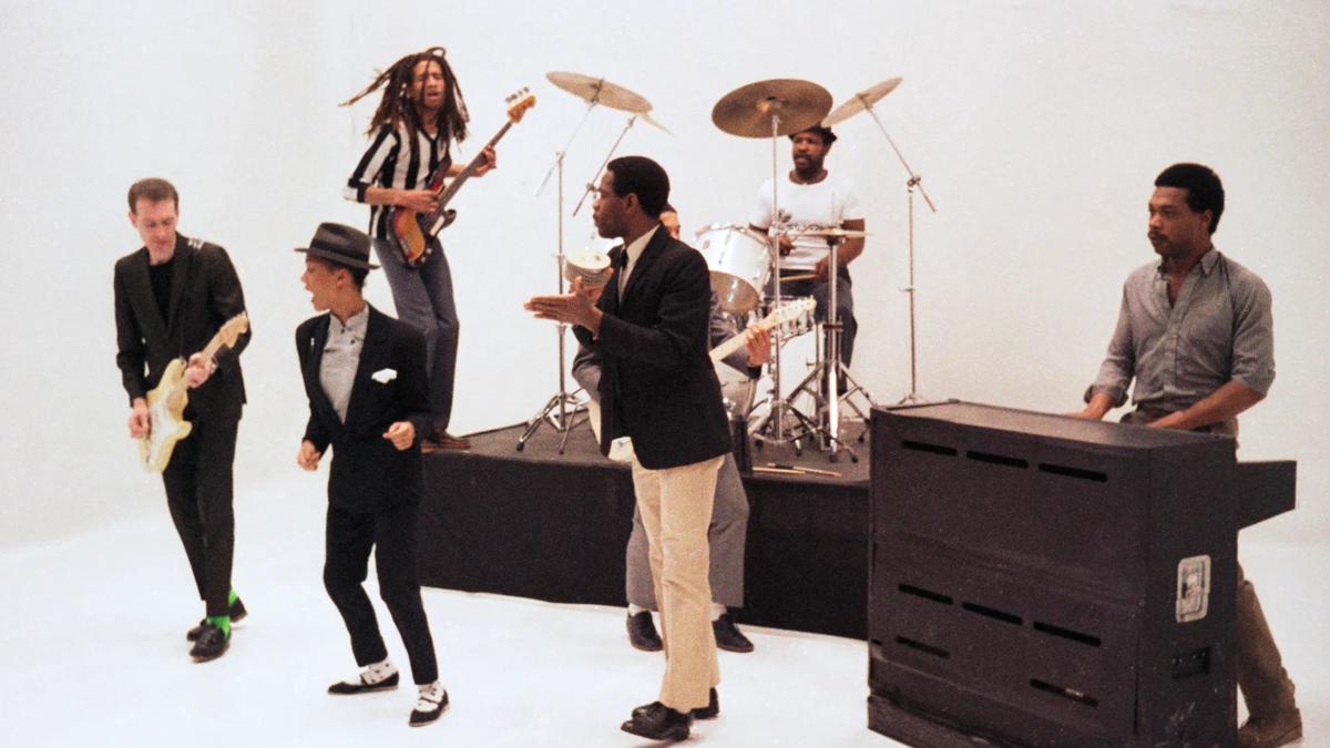 Still from music video for The Selecter, shows the band performing against a white backdrop