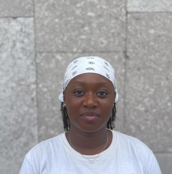 A portrait of Patricia Luyindula taken in front of a grey concrete wall