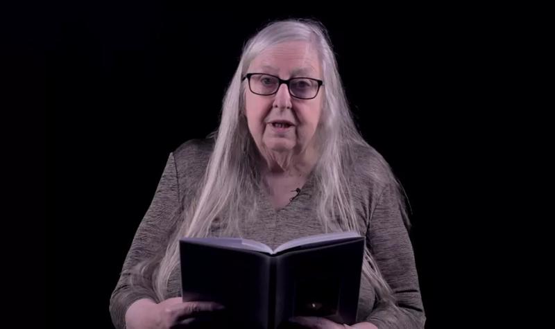 Eiléan Ní Chuilleanáin, an older White woman with long white hair and glasses reads from their TS Eliot Prize shortlisted collection against a black background