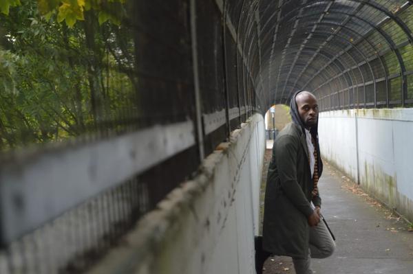 A man posing in a tunnel wearing a hoodie