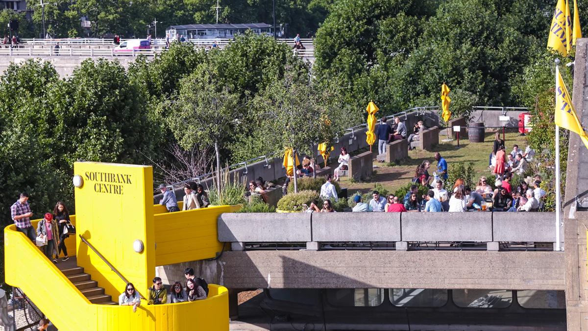 The Southbank Centre's Queen Elizabeth Hall Roof Garden in the summer with people sat around chatting, as seen from the Level 5 balcony of the Royal Festival Hall