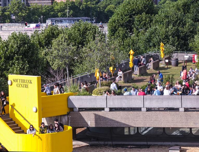 The Southbank Centre's Queen Elizabeth Hall Roof Garden in the summer with people sat around chatting, as seen from the Level 5 balcony of the Royal Festival Hall