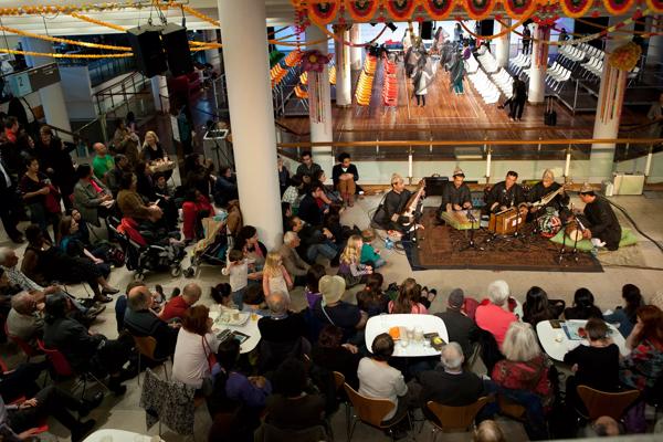 An event in the Royal Festival Hall Clore Ballroom as part of Alchemy 2011; sufi musicians are seated on a rug, whilst an audience sit around them; behind them chairs and South Asian decorations can be seen on the Clore Ballroom