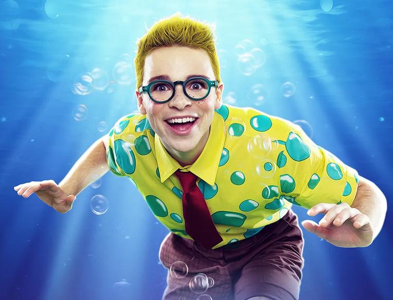A boy wearing a yellow shirt with bubbles on underwater