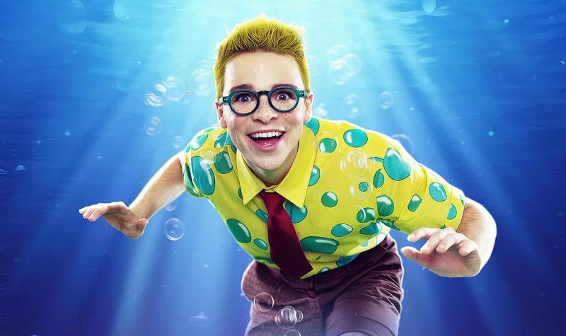 A boy wearing a yellow shirt with bubbles on underwater