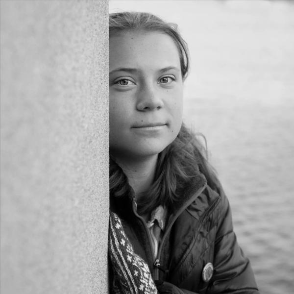 Greta Thunberg by the sea, wearing mittens and puffer jacket 